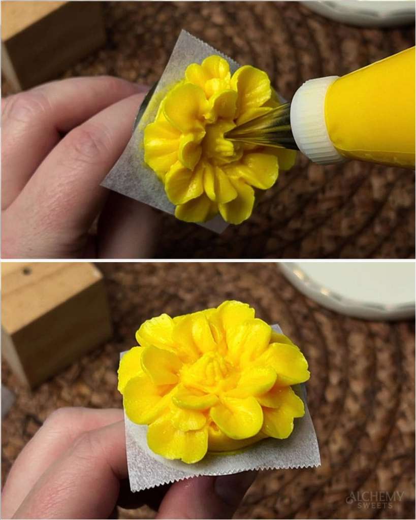 Close-up of a Wilton #2 tip piping small buttercream balls into the center of a yellow marigold to form the puffy, pincushion-like middle.